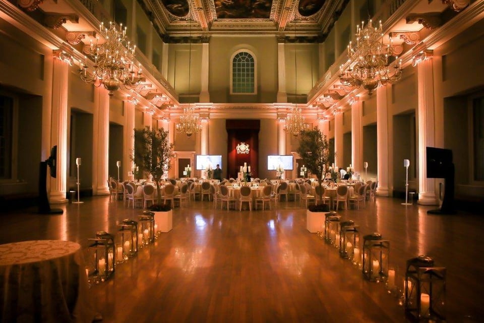 The Banqueting House in Whitehall dressed for dinner with candlelight, lanterns and trees along the hall.
