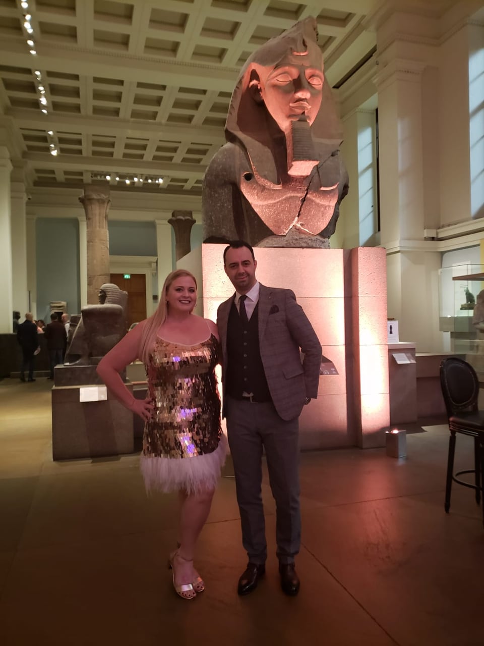 Jennifer and a guest in evening dress in front of the colossal bust of Ramesses II in the British Museum's Egyptian sculpture gallery.