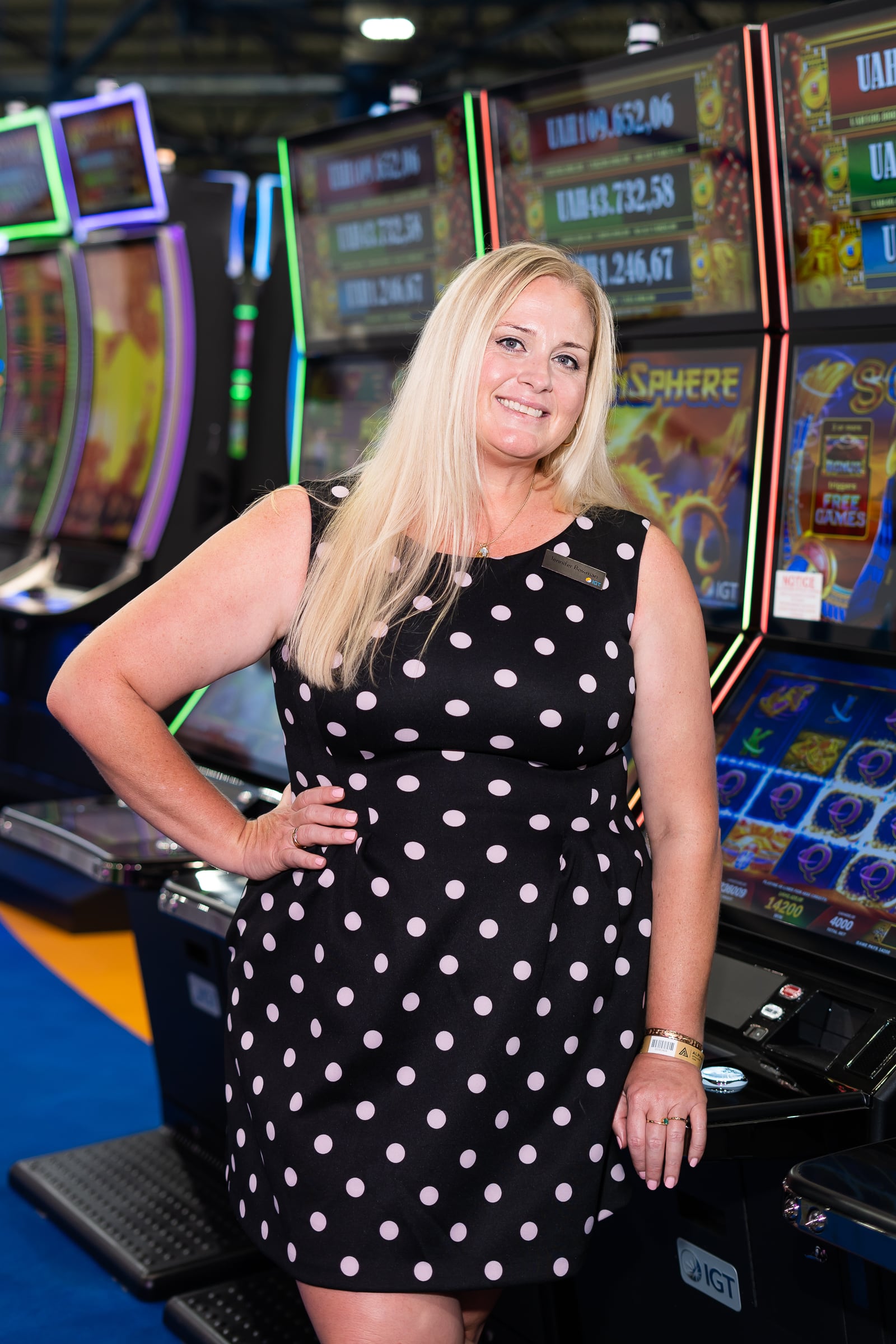 Jennifer beside a large gaming cabinet on a trade-show floor in Kyiv.