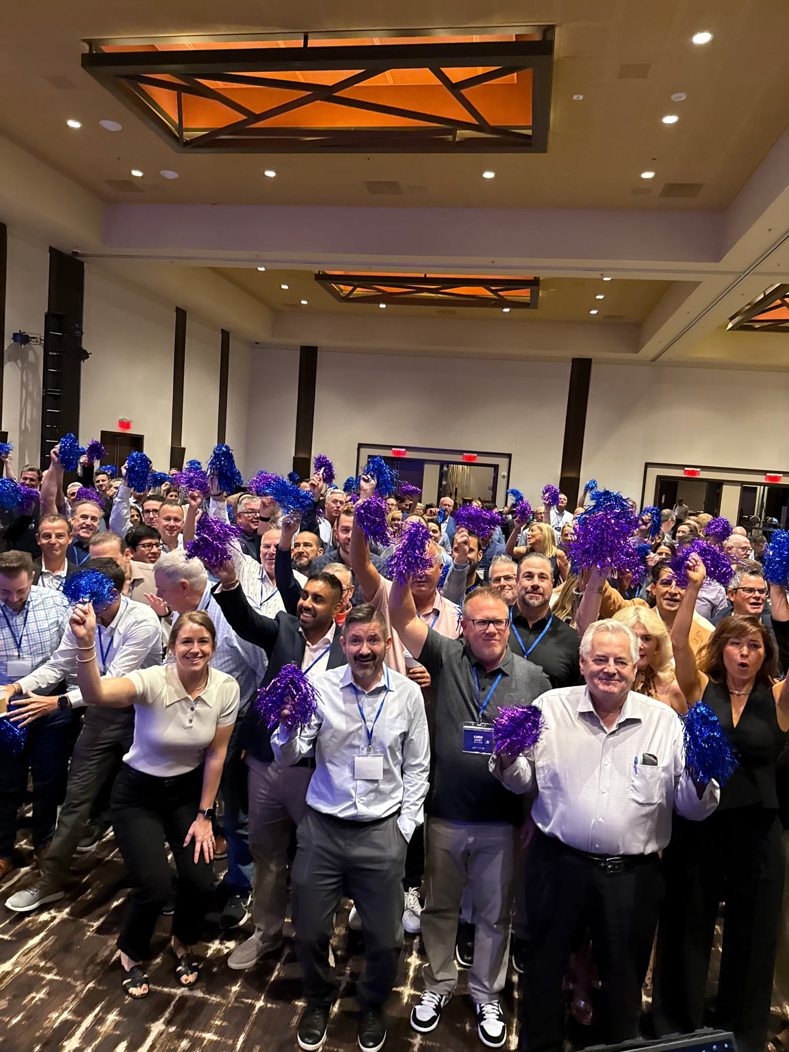 A conference audience on its feet waving blue pom-poms.